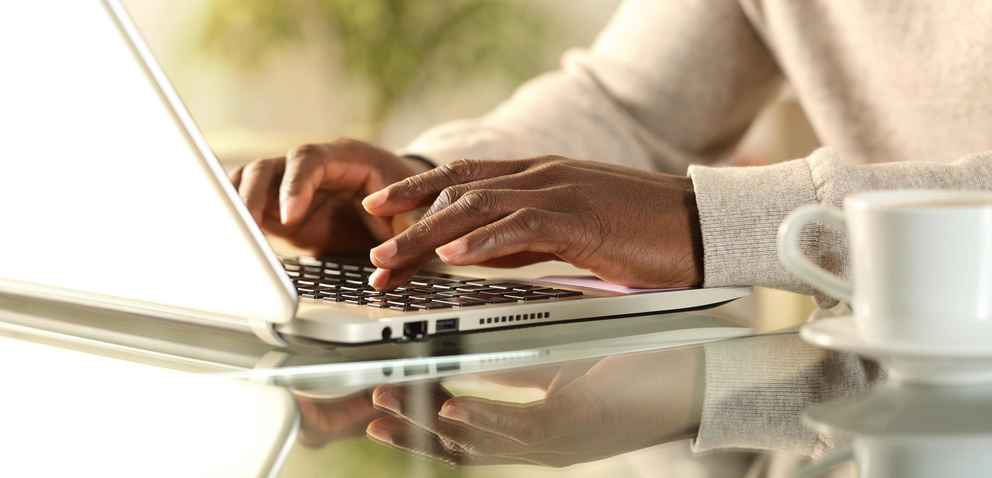African American man's hands typing on a laptop at home